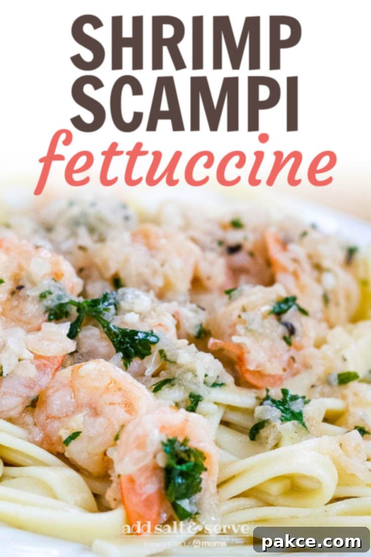White plate with shrimp, minced garlic, and parsley on a bed of fettuccine