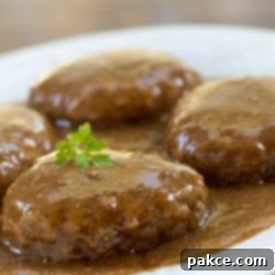 Homestyle Salisbury Steak 2 Close-up of a Salisbury Steak patty covered in brown gravy with parsley garnish.