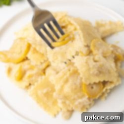 20-Minute Velvety Summer Squash Ravioli 10 Plate of creamy summer squash and cheese ravioli in a cheese sauce with a forkful lifted to the camera.