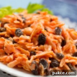 Sweet and Crunchy Carrot Raisin Delight 2 Carrot Raisin salad on a white plate garnished with celery leaves