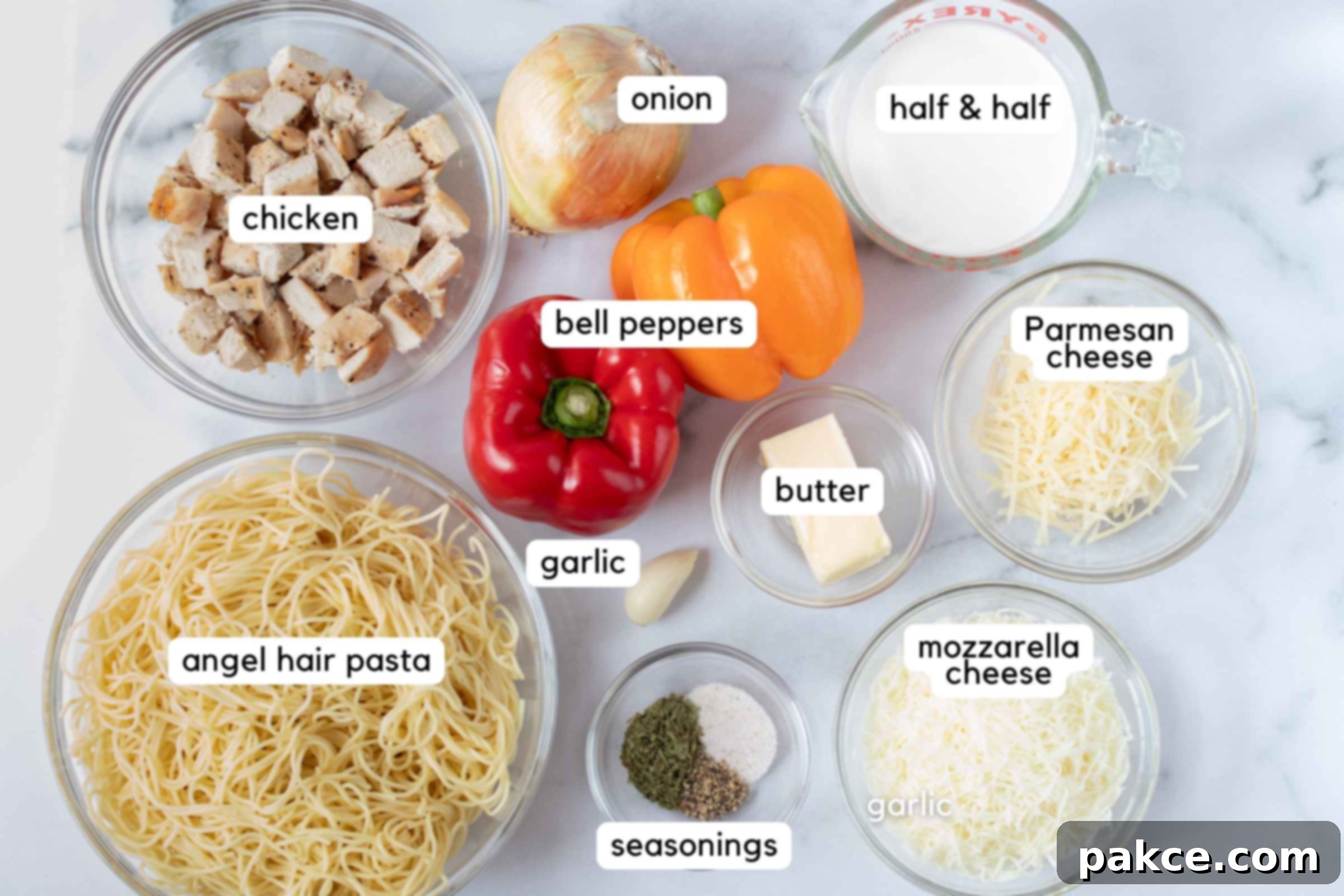 Chicken Pepper Pasta A flat lay of all the ingredients required for chicken pepper pasta: cooked chicken, sliced yellow onion, red bell pepper, yellow bell pepper, half and half, butter, minced garlic, shredded Parmesan cheese, shredded mozzarella cheese, cooked angel hair pasta, and a small bowl with tarragon, pepper, and salt.