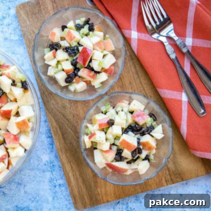 apple-raisin-salad-sq-min-2 Overhead view of salad with chopped apples, raisins, and celery with a coral plaid towel and two forks.